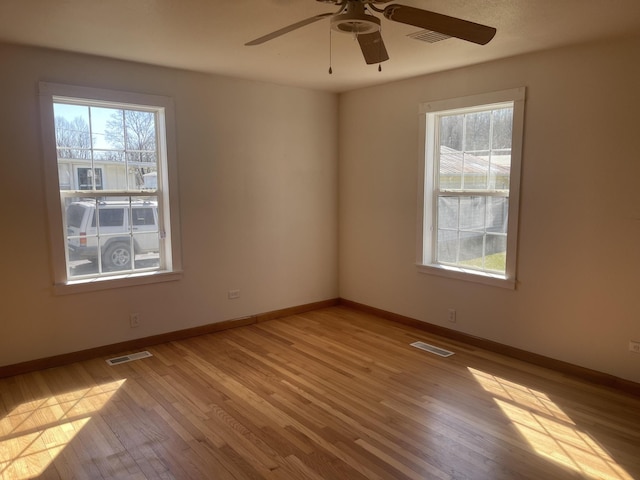 spare room featuring wood finished floors, visible vents, and a healthy amount of sunlight