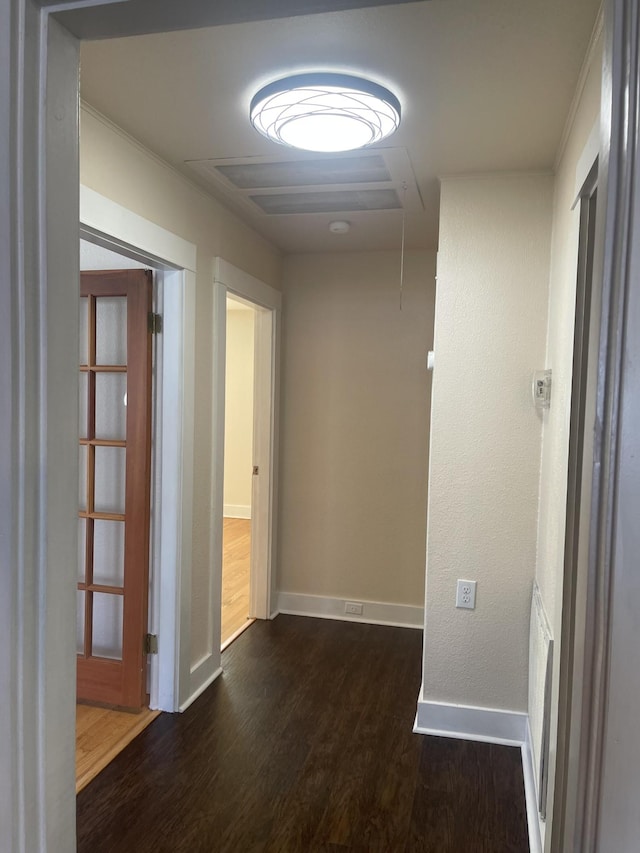 corridor featuring attic access, dark wood-type flooring, and baseboards