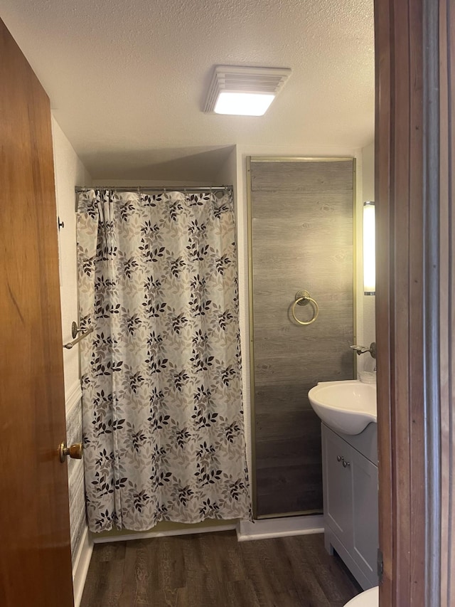 bathroom with a textured ceiling, wood finished floors, vanity, and a shower with curtain