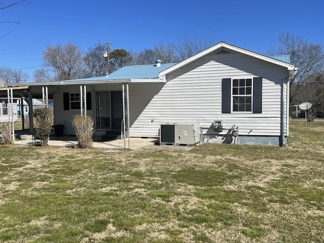 rear view of property featuring metal roof, a yard, a patio area, and central air condition unit