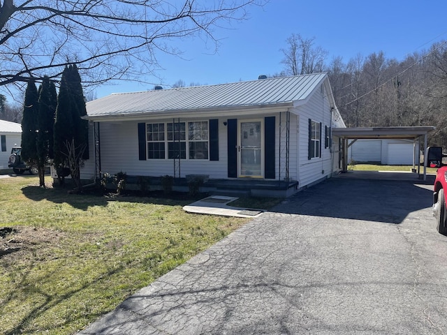 view of front facade featuring metal roof, covered porch, driveway, a detached carport, and a front lawn