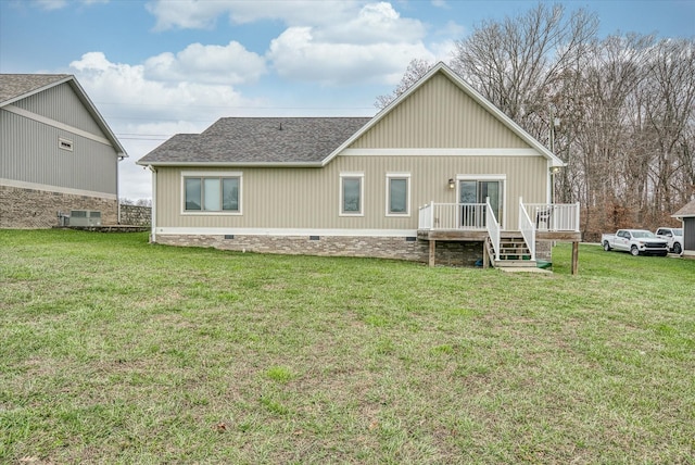 rear view of house with roof with shingles, crawl space, a wooden deck, and a lawn