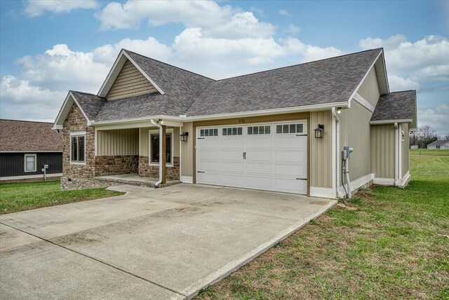 view of front of house with an attached garage, concrete driveway, roof with shingles, a front lawn, and board and batten siding