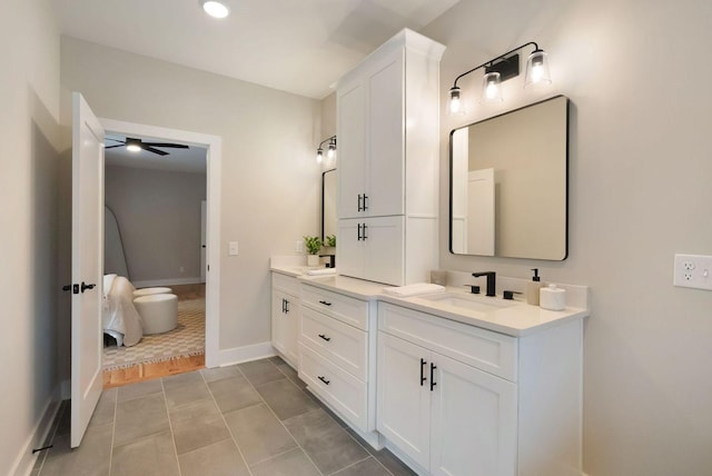 bathroom with double vanity, ceiling fan, a sink, baseboards, and tile patterned floors