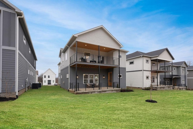 back of property with a balcony, central AC unit, and a yard