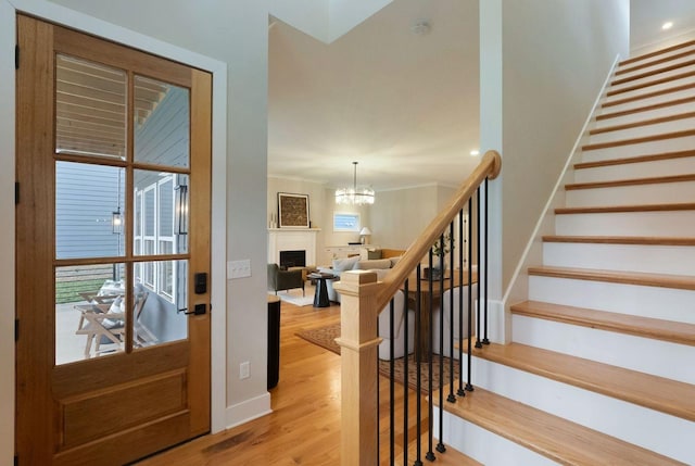 foyer featuring ornamental molding, light wood finished floors, stairway, and baseboards