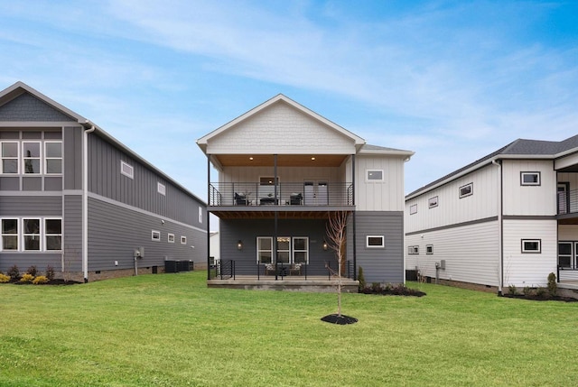 rear view of property with board and batten siding, a yard, and a balcony