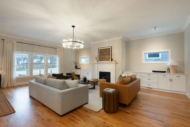 living room featuring ornamental molding, a glass covered fireplace, and light wood-style flooring