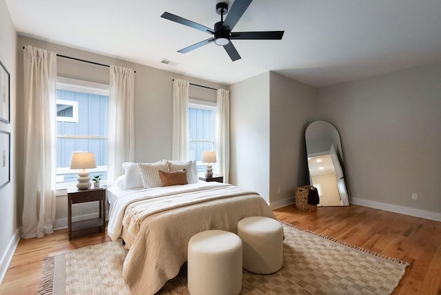 bedroom featuring visible vents, ceiling fan, baseboards, and wood finished floors