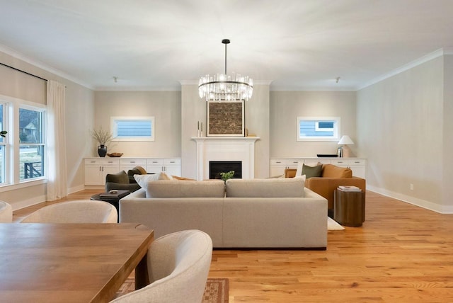 living room featuring light wood finished floors, baseboards, an inviting chandelier, crown molding, and a fireplace