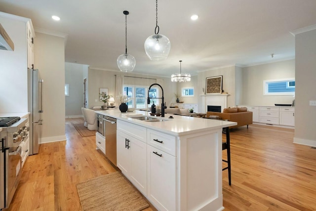 kitchen featuring an island with sink, a breakfast bar, stainless steel appliances, crown molding, and a sink