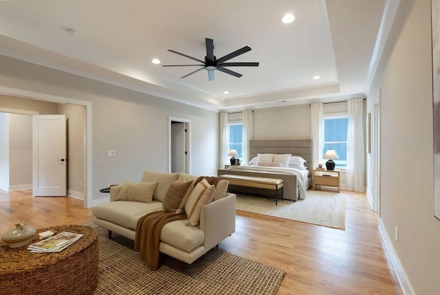 bedroom with light wood-style flooring, a tray ceiling, baseboards, and recessed lighting