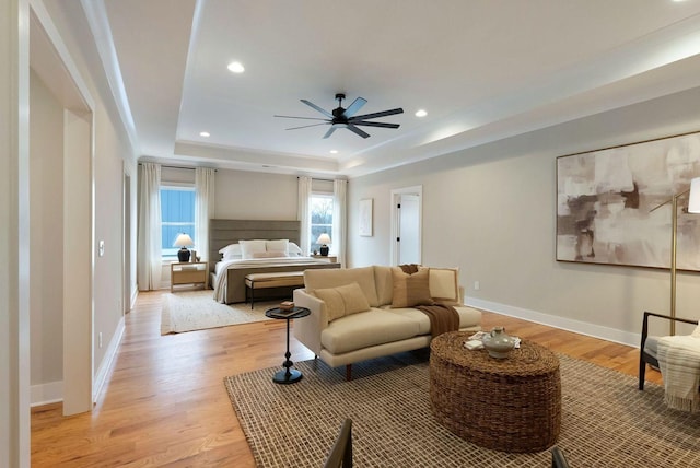 bedroom featuring a tray ceiling, light wood-style flooring, baseboards, and recessed lighting