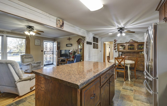 kitchen featuring freestanding refrigerator, stone finish floor, and open floor plan