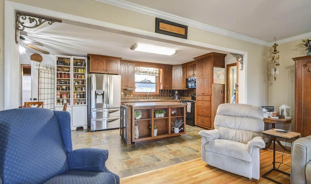 kitchen featuring crown molding, decorative backsplash, open floor plan, a sink, and black appliances