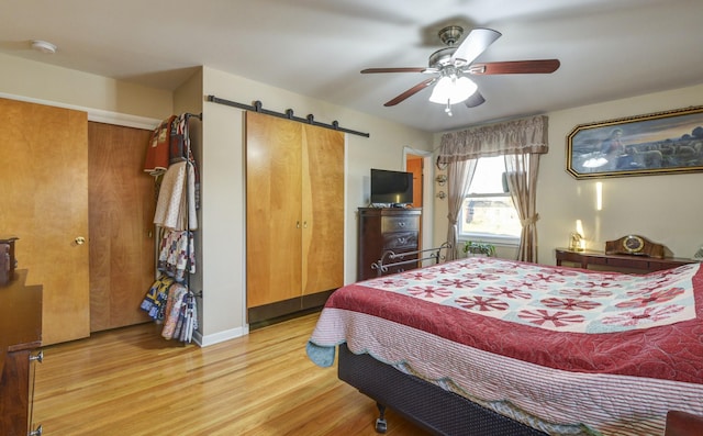 bedroom with a barn door, a ceiling fan, and wood finished floors