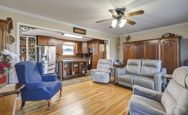 living room with light wood-style flooring, a ceiling fan, and crown molding