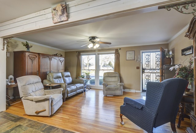 living room with ornamental molding, light wood-type flooring, ceiling fan, and baseboards