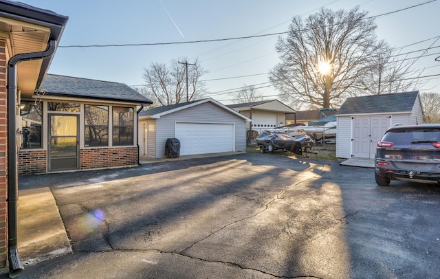 view of property exterior with an outbuilding, a sunroom, brick siding, and a garage