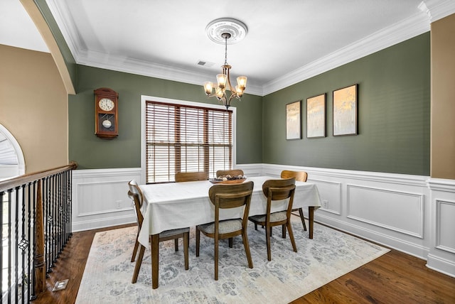 dining space featuring visible vents, a wainscoted wall, ornamental molding, dark wood-style flooring, and a chandelier