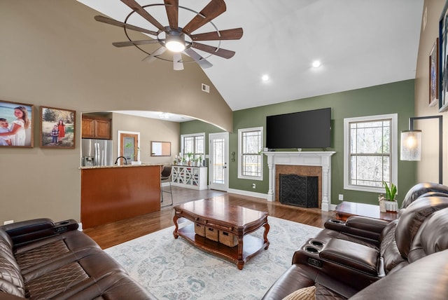 living room with high vaulted ceiling, a fireplace, ceiling fan, and wood finished floors