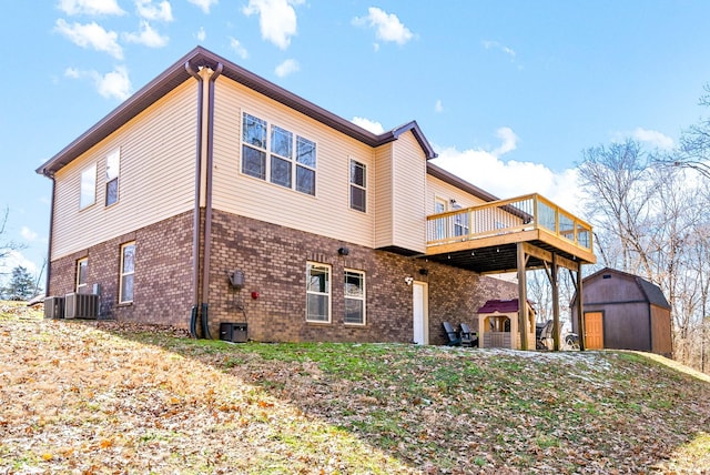 back of house with a storage shed, brick siding, a deck, and an outdoor structure