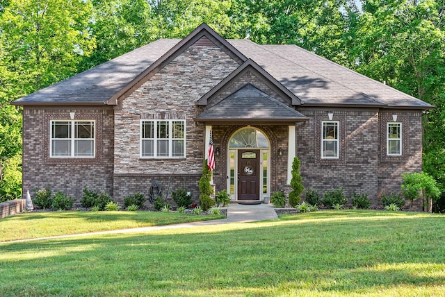 view of front of house featuring roof with shingles, a front lawn, and brick siding