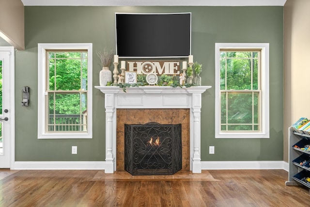 unfurnished living room with a fireplace, baseboards, a wealth of natural light, and wood finished floors