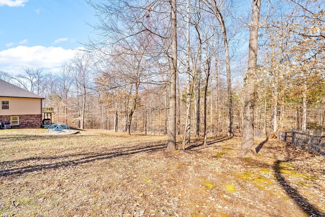 view of yard featuring a wooded view and fence