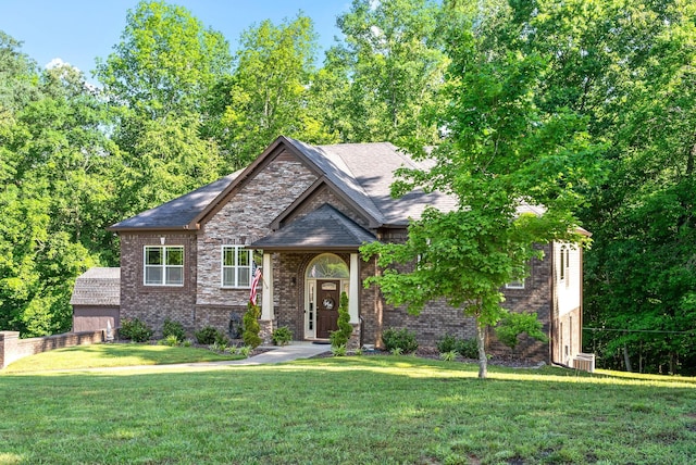 view of front facade with brick siding, roof with shingles, and a front yard