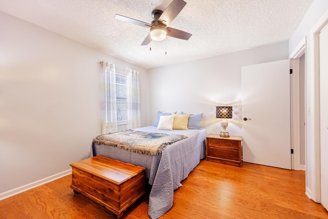 bedroom with ceiling fan, a textured ceiling, baseboards, and light wood-style floors