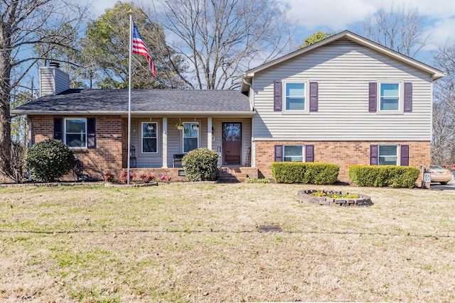 tri-level home featuring a front yard, brick siding, and a chimney