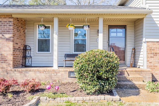 property entrance featuring a porch, crawl space, brick siding, and roof with shingles