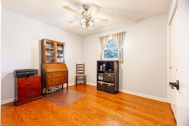 misc room with ceiling fan, a textured ceiling, baseboards, and wood finished floors