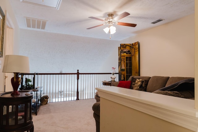 living area featuring visible vents, attic access, carpet, and a ceiling fan