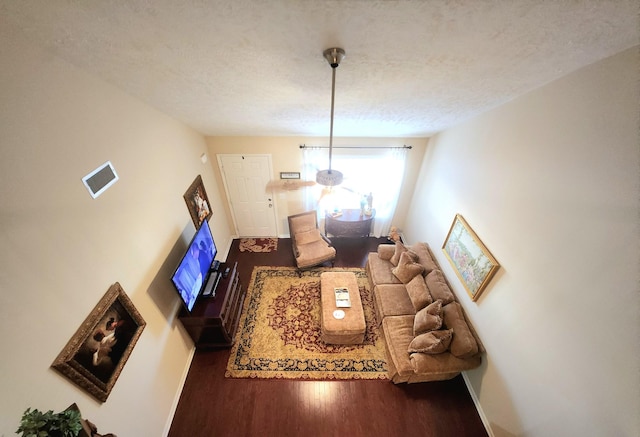 living room featuring a textured ceiling, wood finished floors, visible vents, and baseboards