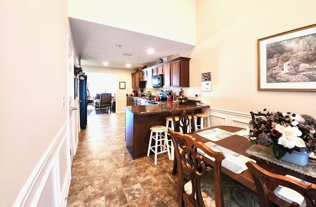 dining area with recessed lighting, wainscoting, and a decorative wall