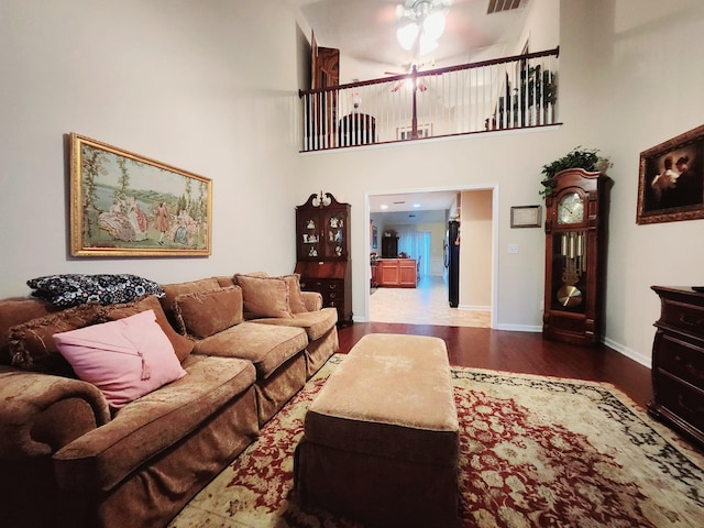 living area with visible vents, ceiling fan, baseboards, a high ceiling, and wood finished floors