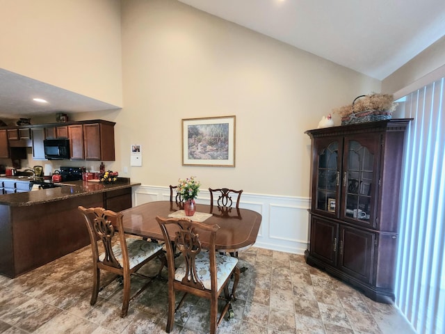 dining area with a decorative wall, wainscoting, and vaulted ceiling