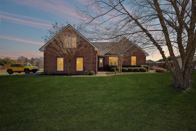 traditional-style home with brick siding, a yard, and fence