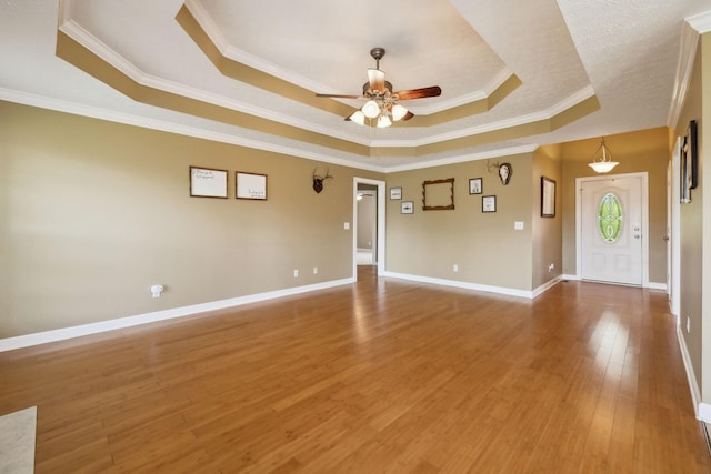 empty room featuring wood finished floors, a ceiling fan, crown molding, and a tray ceiling