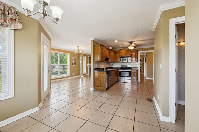 kitchen with a sink, appliances with stainless steel finishes, dark countertops, ornamental molding, and brown cabinetry
