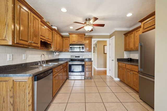 kitchen with dark countertops, a sink, backsplash, and appliances with stainless steel finishes