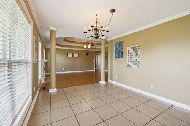 empty room featuring light tile patterned floors, a raised ceiling, crown molding, ornate columns, and ceiling fan with notable chandelier