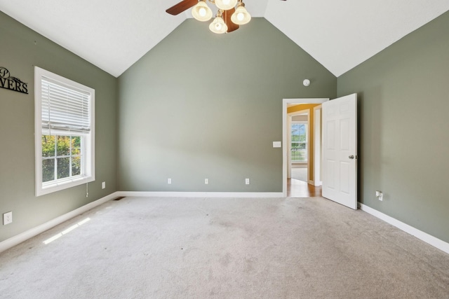 carpeted empty room with baseboards, high vaulted ceiling, and ceiling fan