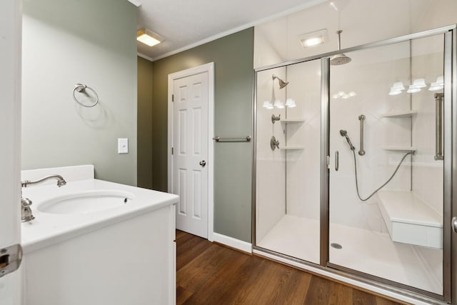 full bathroom featuring a stall shower, ornamental molding, wood finished floors, and vanity