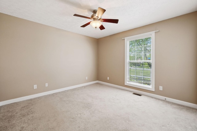 spare room with baseboards, visible vents, ceiling fan, and light colored carpet