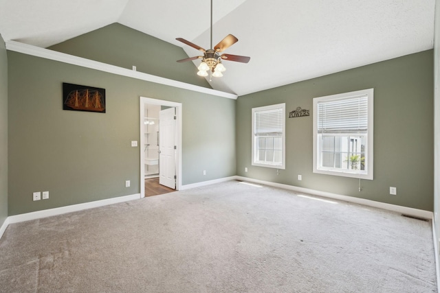 carpeted spare room featuring crown molding, a ceiling fan, visible vents, baseboards, and lofted ceiling