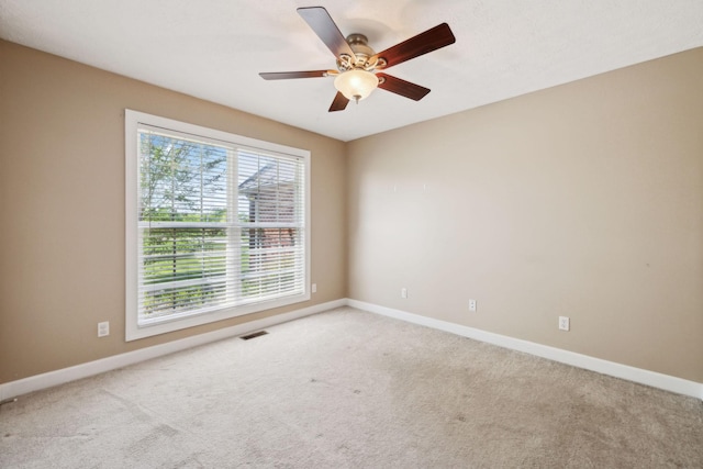 carpeted empty room featuring ceiling fan, visible vents, and baseboards