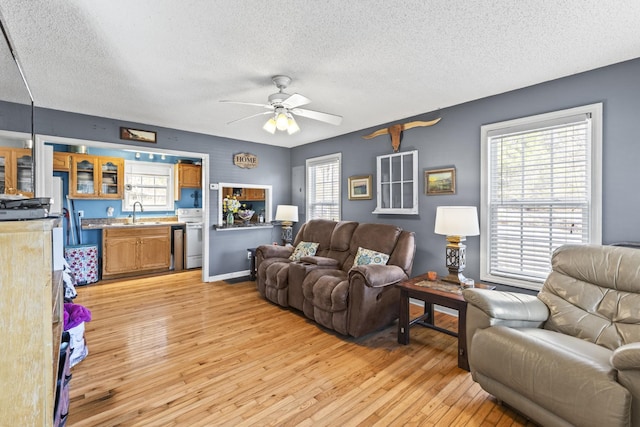 living area with light wood finished floors, a textured ceiling, and a ceiling fan